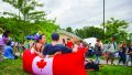 高贵林加拿大国庆日 - 镇中心公园两个人坐在一个充气枕头主席拥有的加拿大国旗