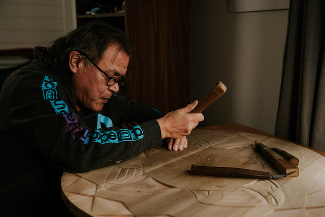 Mowachaht乐队的Nuu-Chah-Nulth艺术家Patrick Amos在雪松雕刻上工作
